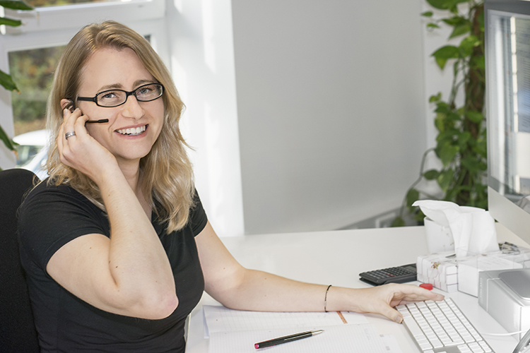 Br24 Services - Persönliche Betreuung: Frau mit Headset sitzt an einem Schreibtisch und lächelt in die Kamera