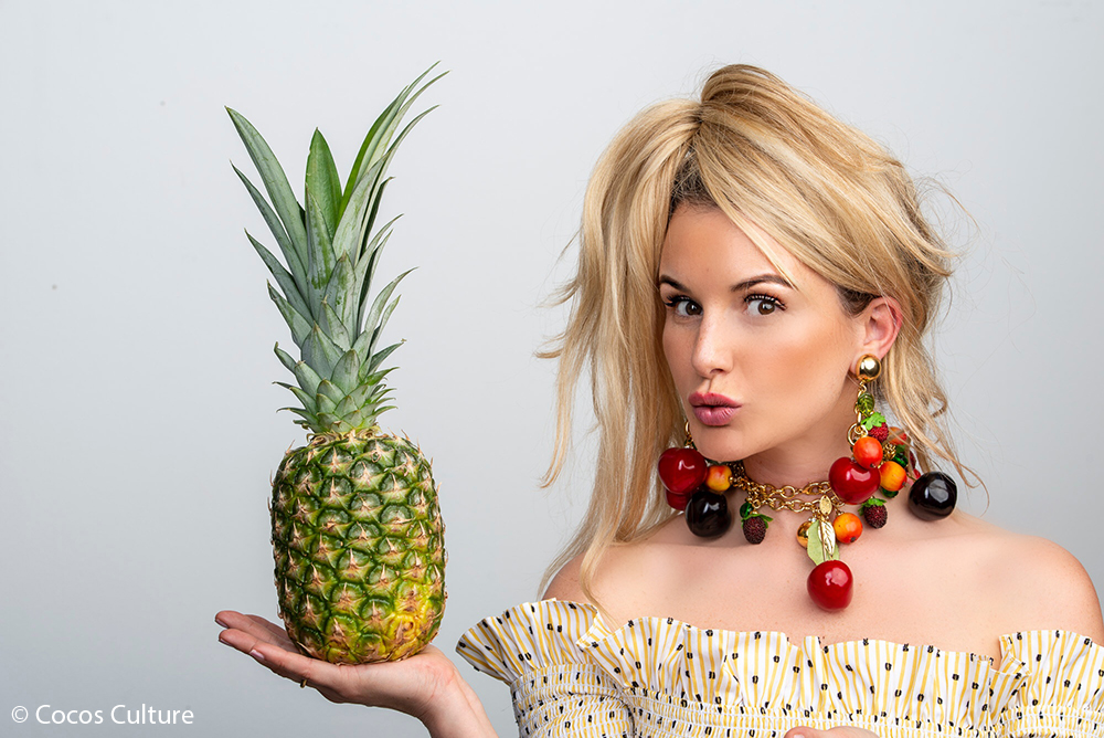 Br24 Werbung & Marketing, Hintergrund entfernen: Porträt einer Frau mit einer Ananas in der Hand vor grauem Hintergrund