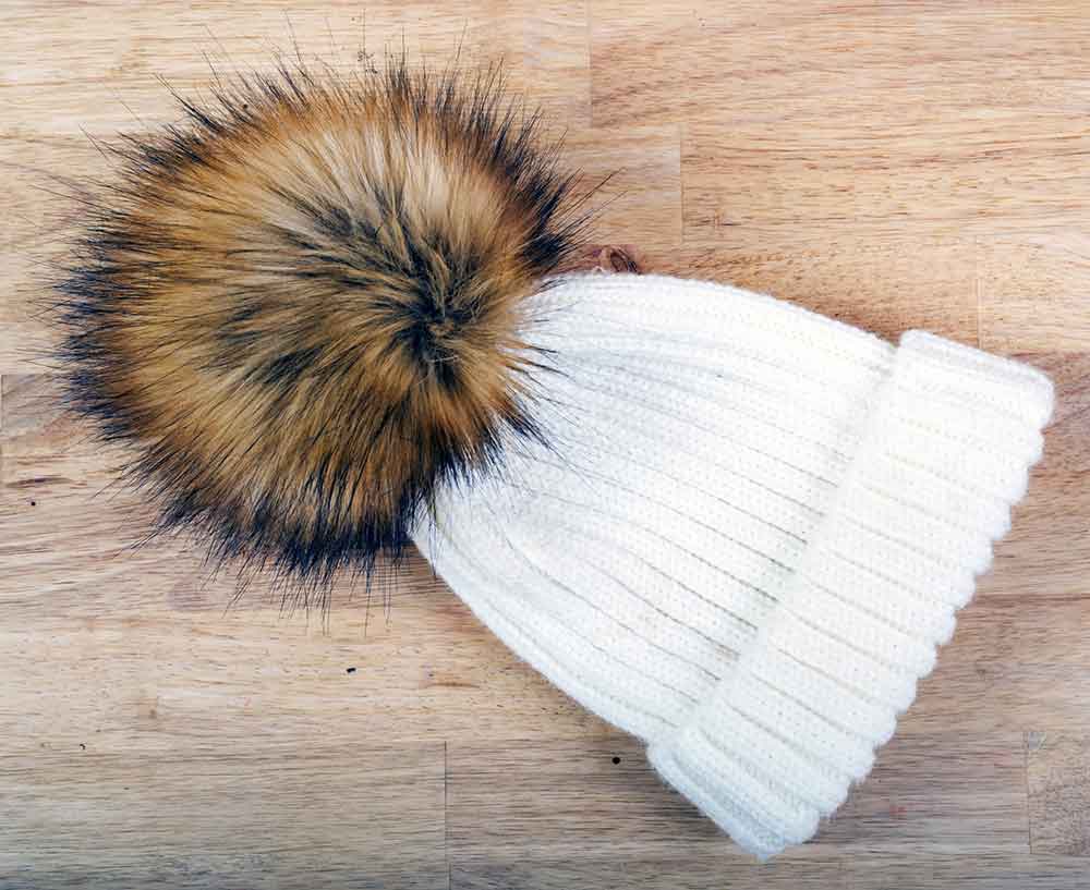 Br24 E-Commerce: woolen hat with a large fur pompom on a wooden background